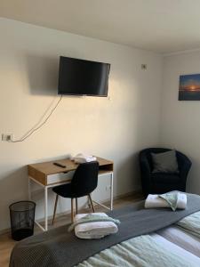 a room with a bed and a desk with a television on the wall at Skammidalur Guesthouse in Vík