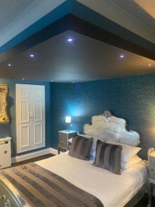 a bedroom with a large bed with a blue wall at The Vine Hotel, Skegness in Skegness