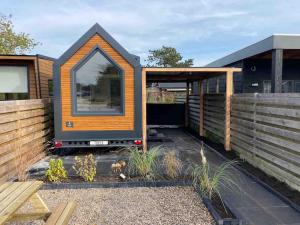 a tiny house with a large window in a yard at Tiny house with sauna & jacuzzi near Amsterdam in Vijfhuizen