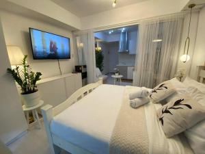 a bedroom with a white bed with a television on the wall at Azure BEACHfront view Aesthetic Minimalist unit in Manila