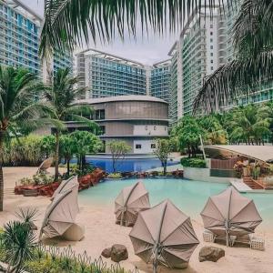 einem Pool mit Sonnenschirmen vor einem Gebäude in der Unterkunft Azure BEACHfront view Aesthetic Minimalist unit in Manila