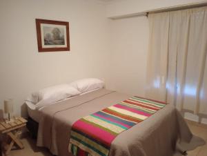 Un dormitorio con una cama con una manta de colores. en departamento el atardecer en Chascomús