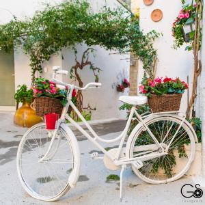 Una bicicleta blanca estacionada frente a un edificio con flores en La Nghioscia, en Grottaglie