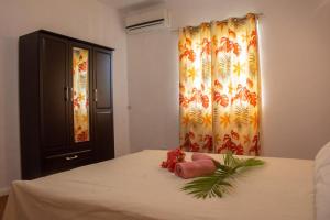 ein Schlafzimmer mit einem Bett mit einem Vorhang und Blumen darauf in der Unterkunft Montaguvilla#3 in Flic-en-Flac