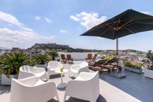 a patio with white chairs and a table and an umbrella at Acropolis Panorama View Penthouse with Private Terraces A Contemporary Parthenon in Athens