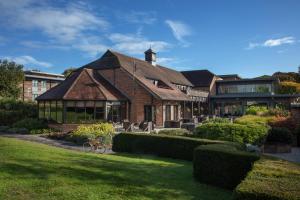 een groot bakstenen huis met een gazon ervoor bij Norton Park Hotel, Spa & Manor House - Winchester in Sutton Scotney