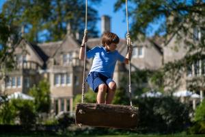 a young boy sitting on a swing in a yard at Woolley Grange - A Luxury Family Hotel in Bradford on Avon