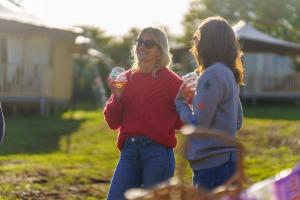 two women are holding wine glasses in a yard at Woolley Grange - A Luxury Family Hotel in Bradford on Avon