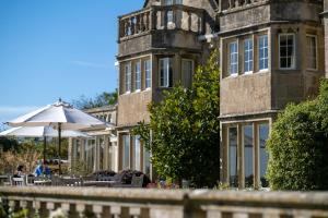 un edificio con una sombrilla delante de él en Woolley Grange - A Luxury Family Hotel, en Bradford on Avon