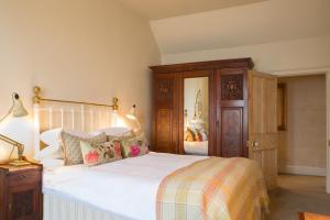 a bedroom with a large white bed and a wooden cabinet at Woolley Grange - A Luxury Family Hotel in Bradford on Avon