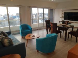 ein Wohnzimmer mit Stühlen, einem Tisch und einem TV in der Unterkunft Encantador apartamento en Miraflores in Lima
