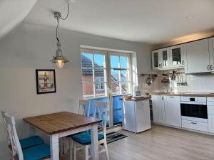 a kitchen with white cabinets and a table with chairs at Haus-Halli-Een-Whg-07 in Sankt Peter-Ording