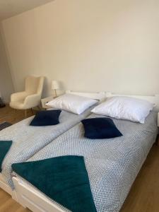- un lit blanc avec des oreillers bleus et une chaise dans l'établissement Mieszkania Osmolickie Puławy Azoty, à Puławy