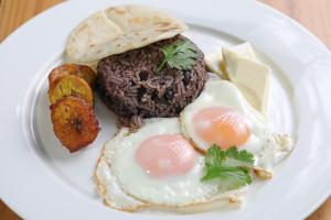 a plate of food with eggs and meat and bread at OPacifico Hotel Boutique in Playa Naranjo