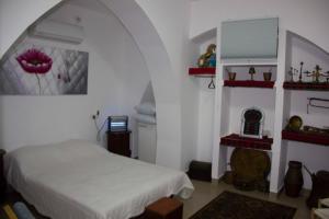 a bedroom with a white bed and red shelves at Shamokh House in Acre