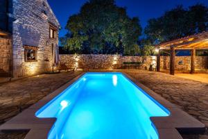 una piscina blu in un cortile di notte di MY DALMATIA - Authentic villa Malou with private swimming pool a Stankovci