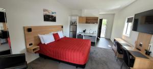a bedroom with a red bed and a television at Sierra Motel and Apartments in Omarama