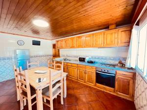 una cocina con armarios de madera, mesa y sillas en Casinha dos Cubos, en Gerês