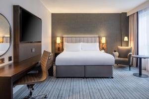 a hotel room with a bed and a desk and a television at DoubleTree by Hilton London Chelsea in London