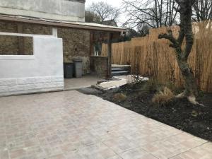 a backyard with a wooden fence and a patio at Cottage de charme proche de Paris in Fontenay-en-Parisis