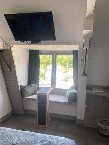 1 dormitorio con asiento junto a la ventana y TV de pantalla plana en De Bloesem, en Cothen