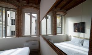 um pequeno quarto com uma cama e janelas em Piazza Mascheroni Home em Bérgamo