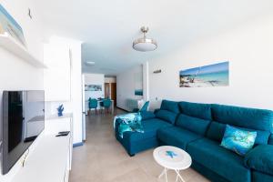 a living room with a blue couch and a table at Calypso in El Cotillo