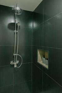a bathroom with a shower with a black wall at ONE LODGE Pattaya in Pattaya Central