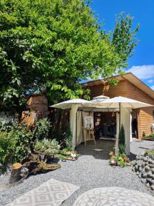 un jardín con sombrilla y una casa en Leftraro Lodge Urbano en Villarrica