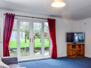 a living room with red curtains and a tv at Crossways Cottage Annex in Chepstow