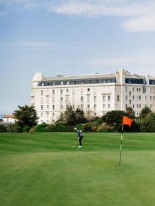a man playing golf in front of a building at Studio phare de Biarritz Résidence Régina Golf in Biarritz