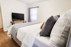 uma cama branca com almofadas e uma televisão num quarto em Cozy and Spacious Home in Ogden em Ogden