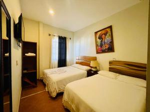 una habitación de hotel con 2 camas y un cuadro en la pared en Hotel León Inn, en León