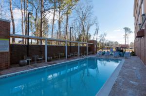 a swimming pool with tables and chairs next to a building at Home2 Suites By Hilton Charlotte Belmont, Nc in Belmont