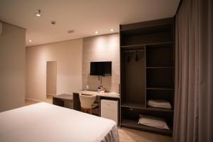 a bedroom with a bed and a desk with a computer at Zahara Hotel in Limeira +28 photos