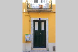 a green door on a yellow building with a balcony at Home Lisbon 2 in Lisbon