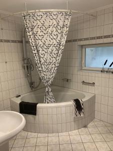 eine Badewanne im Bad mit einem Duschvorhang in der Unterkunft Maison Grande Fleur in Metterich