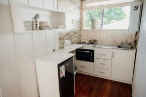 una pequeña cocina con armarios blancos y fregadero en Leftraro Lodge Urbano en Villarrica