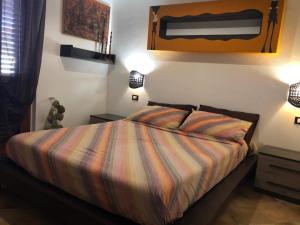 a bedroom with a bed with a striped comforter and two lamps at B&B Il Mirto Bianco in San Giovanni Suergiu