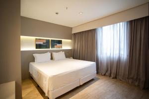 a bedroom with a white bed and a window at Zahara Hotel in Limeira