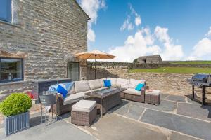 patio con divano, ombrellone e griglia di Dallicar House a Settle