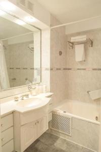 a bathroom with a sink and a tub and a mirror at Hotel HR Plaza Luxor in Buenos Aires