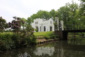una casa blanca con un puente sobre un río en De Bloesem en Cothen