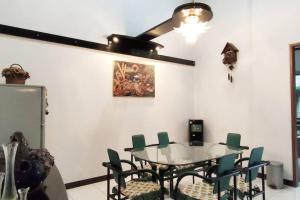 a dining room with a glass table and green chairs at Villa Rumah Oma Lembang 4 Kamar Strategis in Bongkor 1