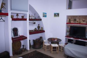 a living room with a tv and a table with stools at Shamokh House in Acre