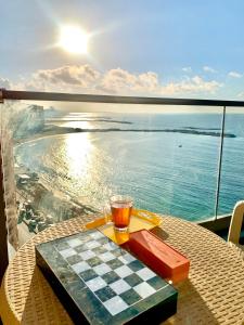 a drink on a chess board on a table with a view of the ocean at شقة فندقية فاخرة luxury apartment sea view in Alexandria