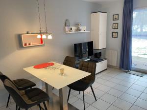 a dining room with a table and chairs and a tv at Haus-Am-Sommerdeich-Whg-12 in Sankt Peter-Ording +4 photos