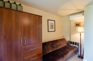 a brown couch in a room with a large cabinet at The Fraser River's Edge B&B Lodge in Chilliwack