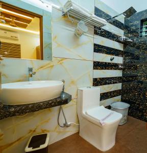a bathroom with a sink and a toilet and a mirror at MARINA SUITES AIRPORT HOTEL in Cochin