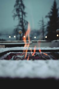 a person standing over a fire in the snow at Hotel Renzi in Folgarida